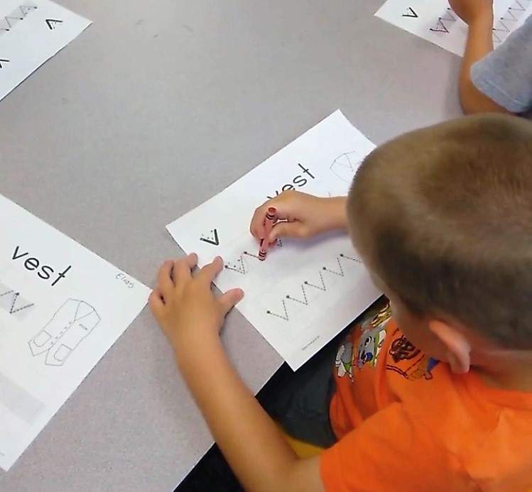 Little boy tracing letters on a piece of paper