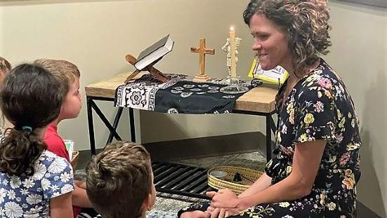 Teacher sitting on the floor teaching young children